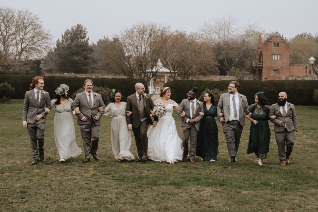 Bridesmaids and groomsmen with the couple in the gardens at Seckford Hall in Suffolk