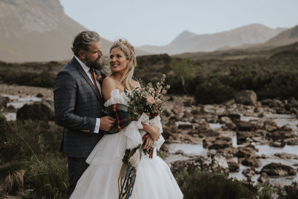 A couple eloping on the Isle of Skye with dramatic mountains behind them