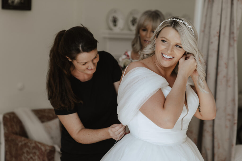 The bride putting on her dress in the bridal suite at Butley Priory in Suffolk