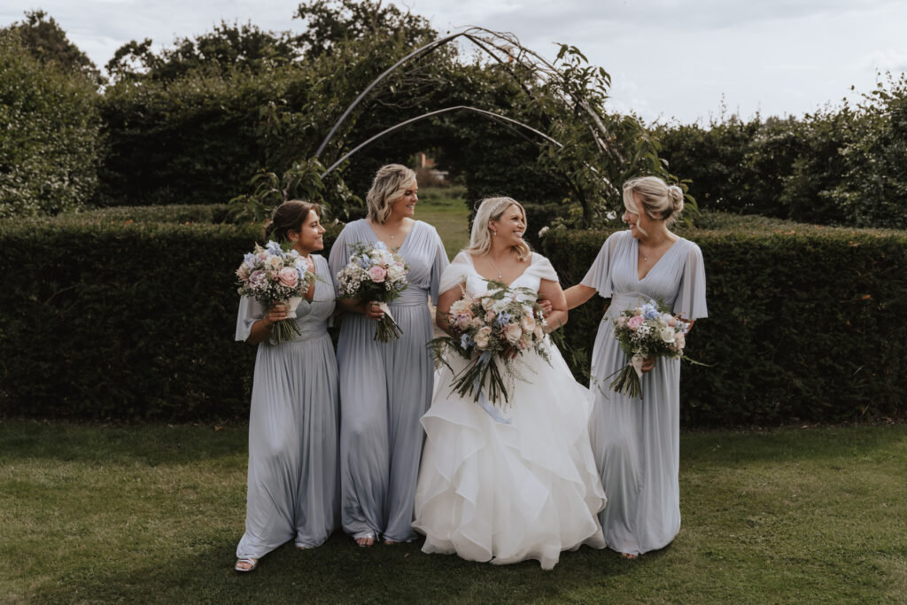 The bride and her bridesmaids walking towards the camera at Butley Priory