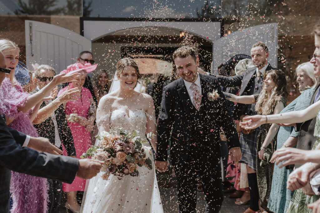 Confetti throwing in the outdoor courtyard at Swallows Nest Barn in Warwickshire