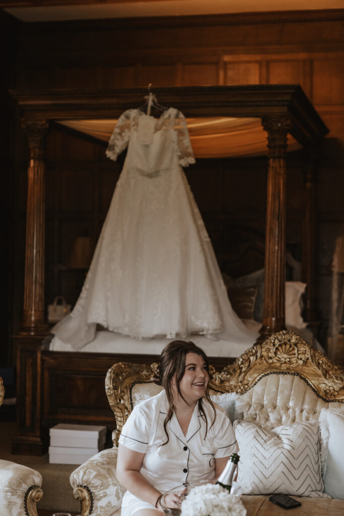 The bride in the bridal suite at Hengrave Hall sat in front of her wedding dress