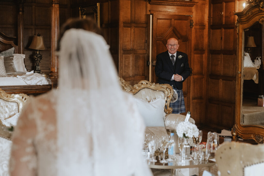 The bride's grandad seeing the bride for the first time in her wedding dress in the bridal suite at Hengrave Hall