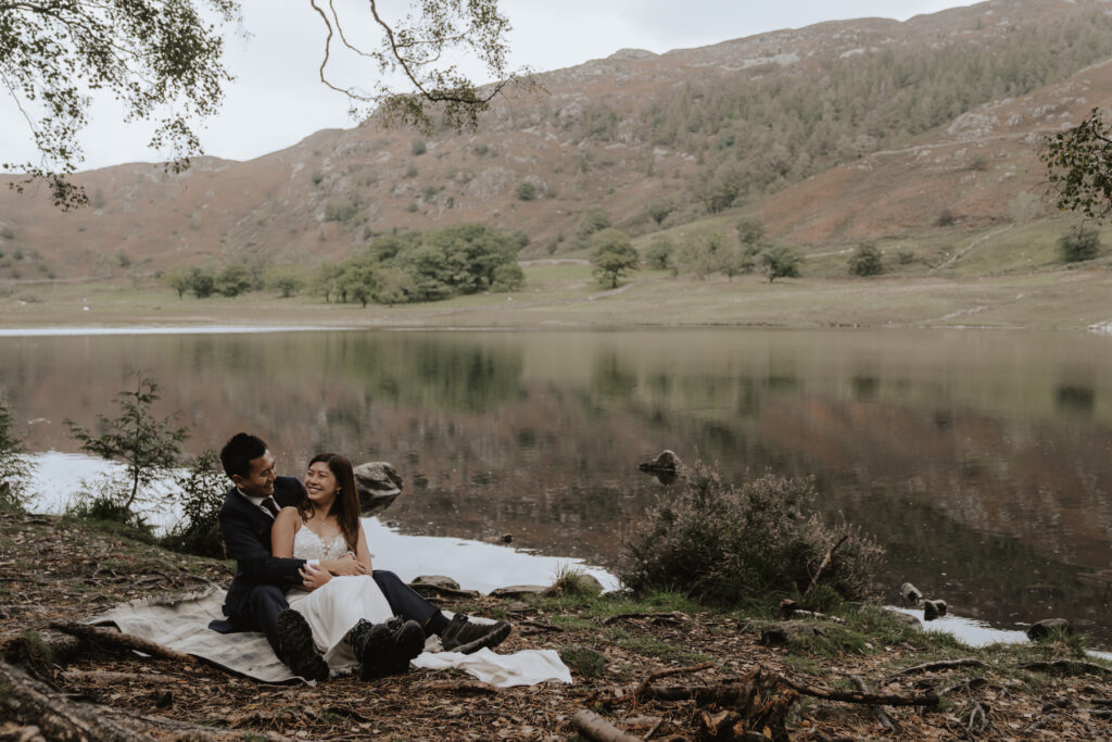 An eloping couple sat by the water during their Lake District elopement