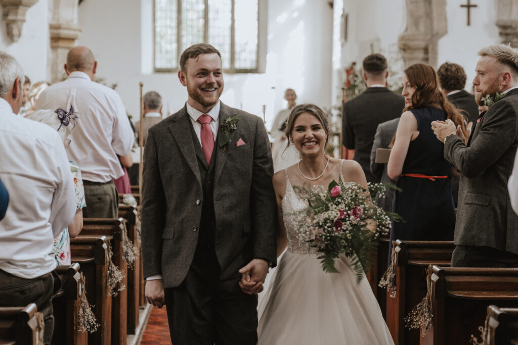 Newlywed couple walking down the aisle after their ceremony captured by a wedding photographer in the midlands