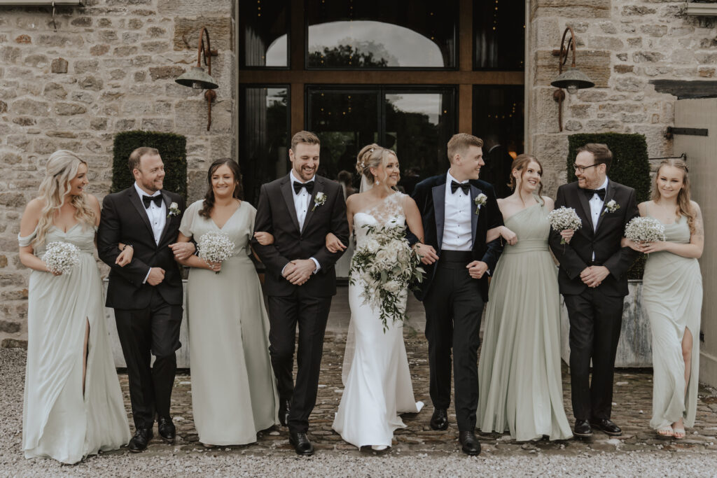 Formal photo of bridesmaids and groomsmen walking away from The Tithe Barn in Yorkshire