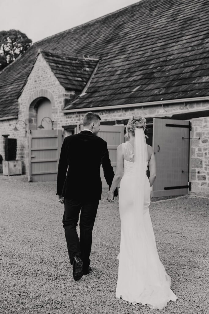 The couple walking towards the Tithe Barn in Yorkshire