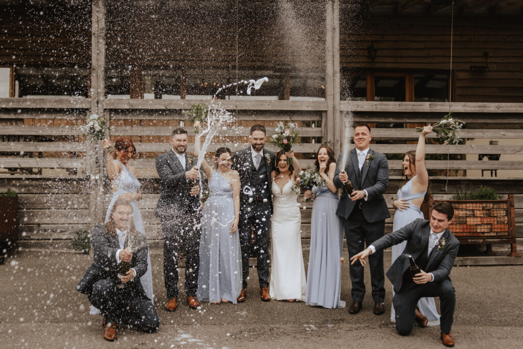 Champagne spray photo with the bridesmaids and groomsmen outside Crockwell Farm