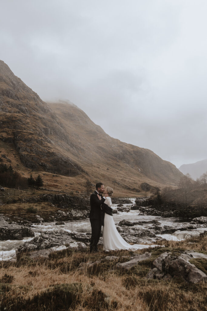 Elopement photographer capturing a couple on their elopement in the Glencoe mountains whilst it rains