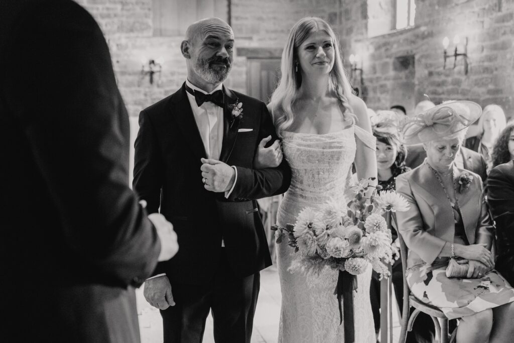 The bride walking down the aisle in the ceremony room at Crockwell Farm