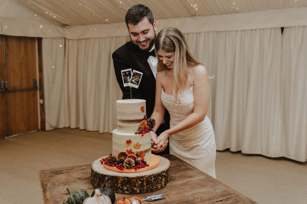 Newly married couple cutting their wedding cake at Northamptonshire wedding venue, Crockwell Farm