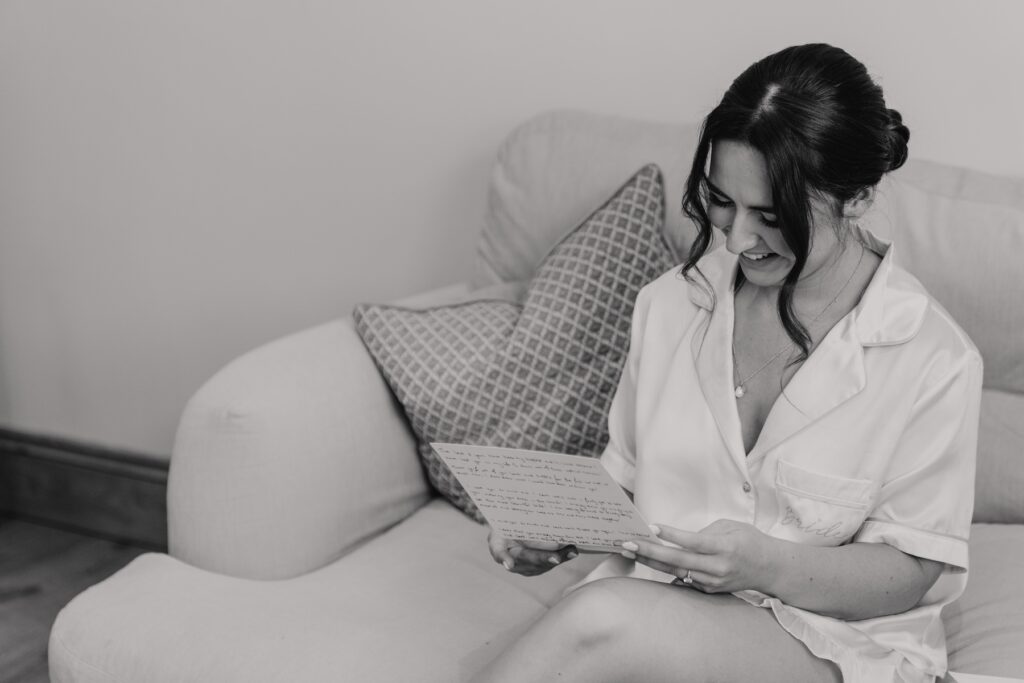 Essex wedding photographer capturing the bride reading a letter in the morning of her wedding at Maidens Barn