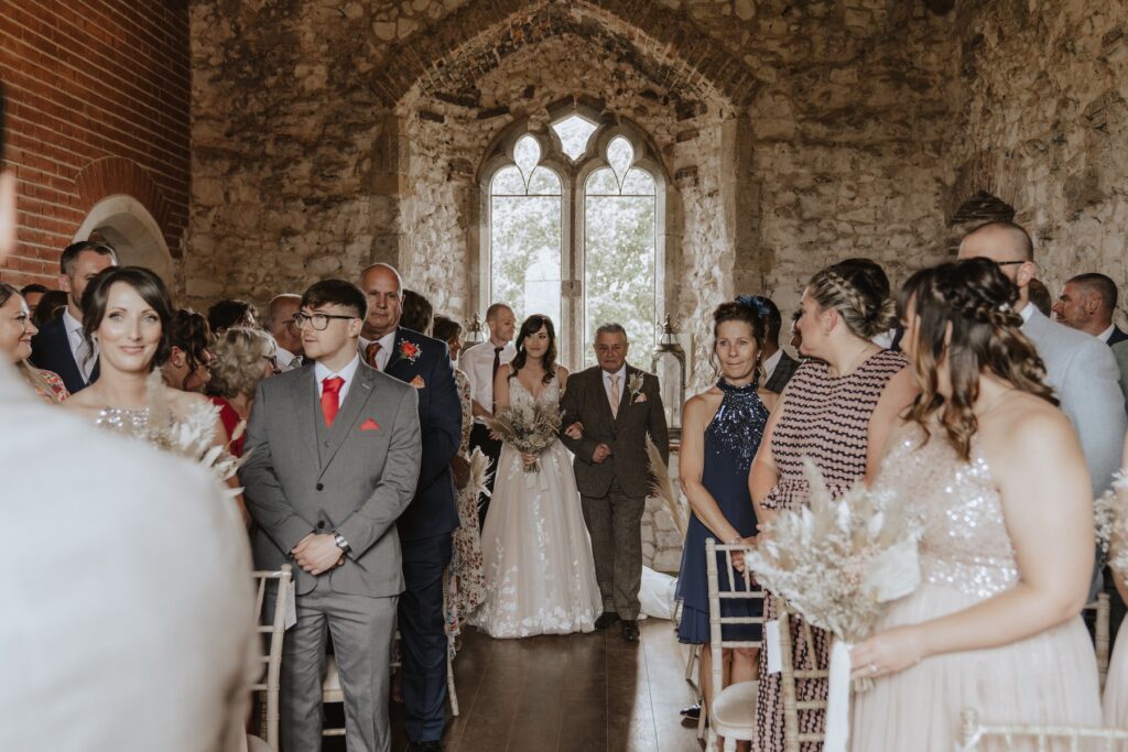 The bride walking down the aisle at Pentney Abbey in Norfolk