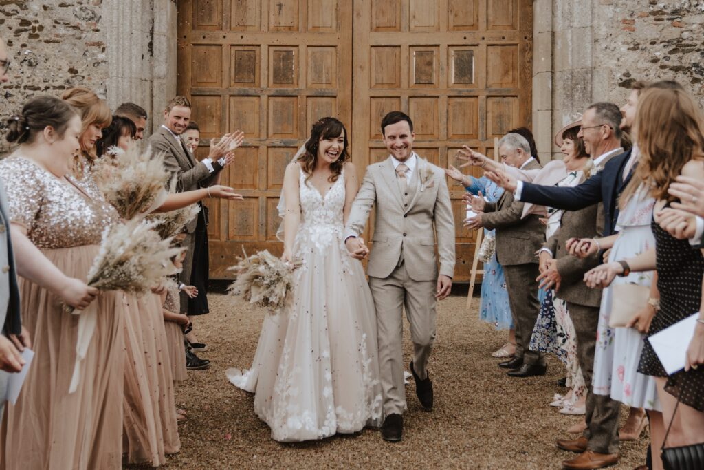 A couple during confetti after getting married at Pentney Abbey in Norfolk