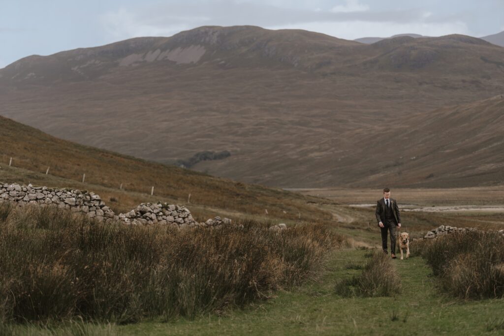 The grooms prep during the Scotland elopement, walking with his dog