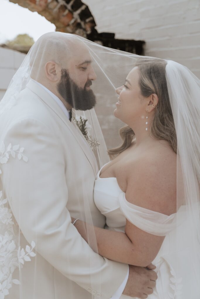 Photos of a newlywed couple under a veil at All Manor of Events in Suffolk