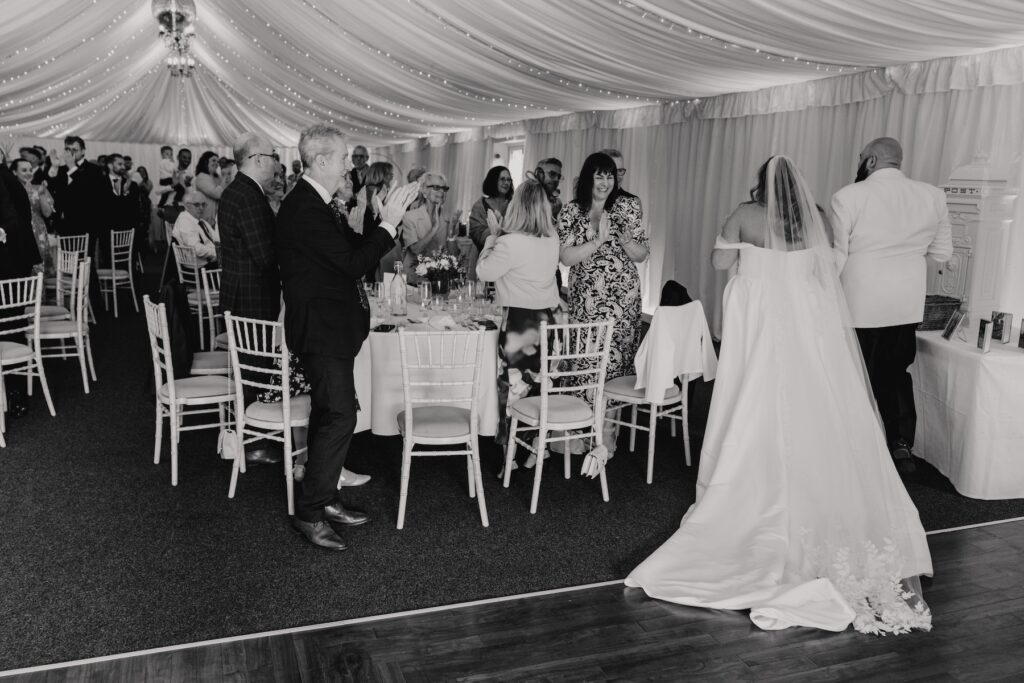 The couple walking into their wedding breakfast room with the guests at All Manor of Events in Suffolk