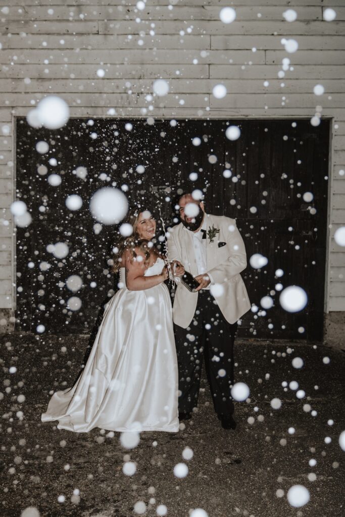 Evening champagne spray as a fun wedding photo idea with the bride and groom at a Suffolk wedding