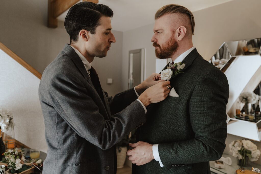 The best man doing the groom's tie during groom's prep at at Bassmead Manor Barns in Cambridge
