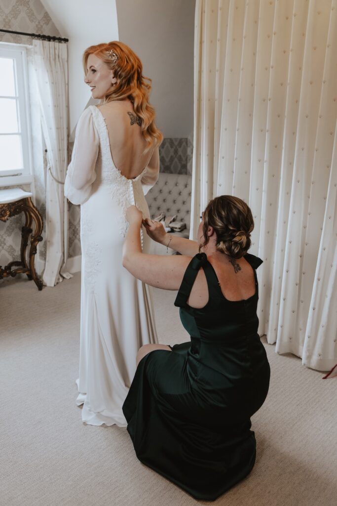 The bride getting into her dress in the morning of her wedding at Bassmead Manor Barns in St Neots
