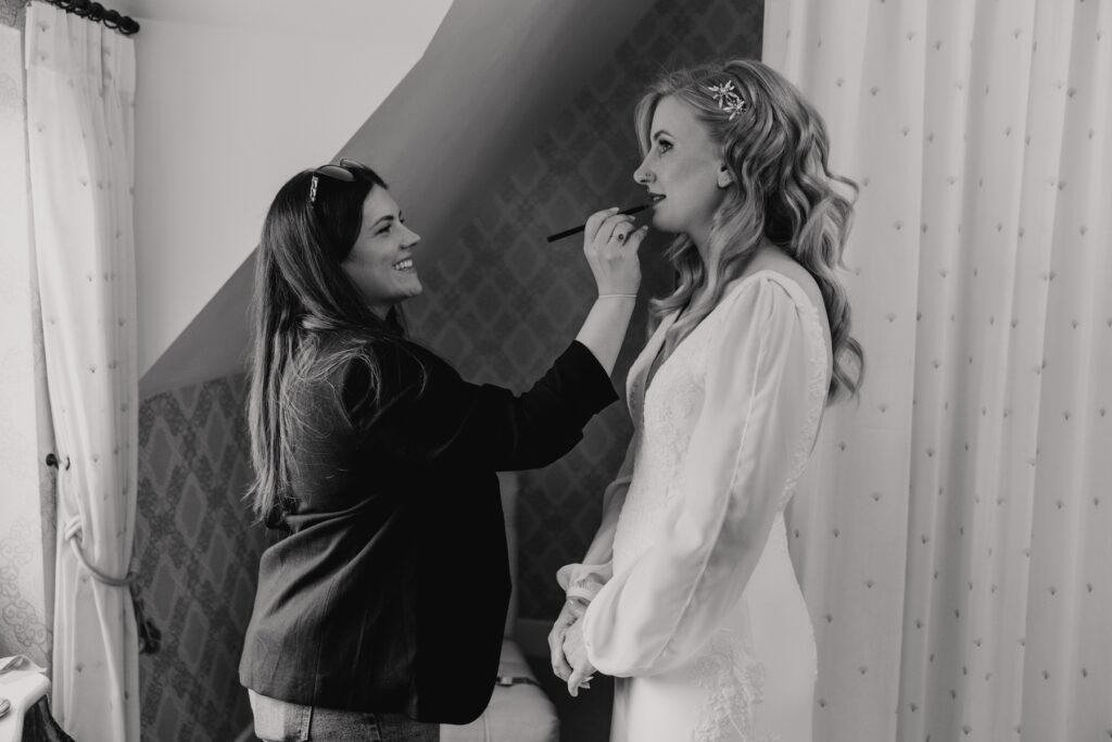 The bride getting her makeup done in the bridal suite at Bassmead Manor Barns in St Neots