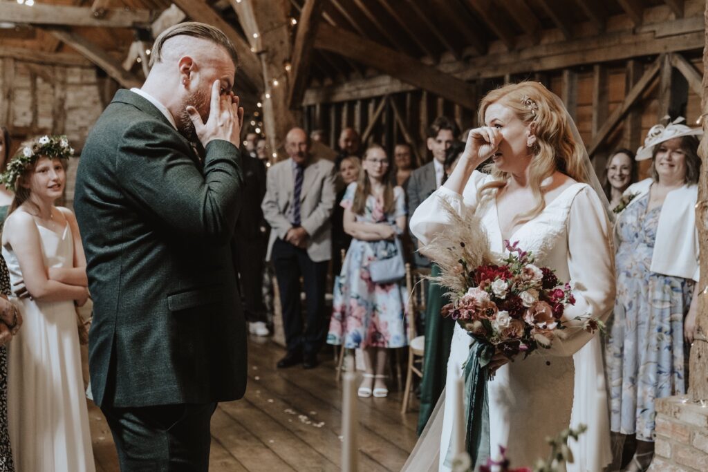 The bride and groom crying during their ceremony at Bassmead Manor Barns in Cambridgeshire