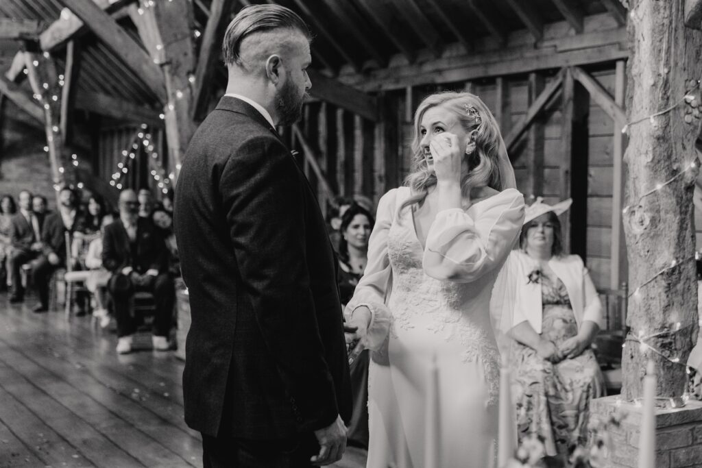 The bride crying during their wedding ceremony at Bassmead Manor Barns in Cambridge