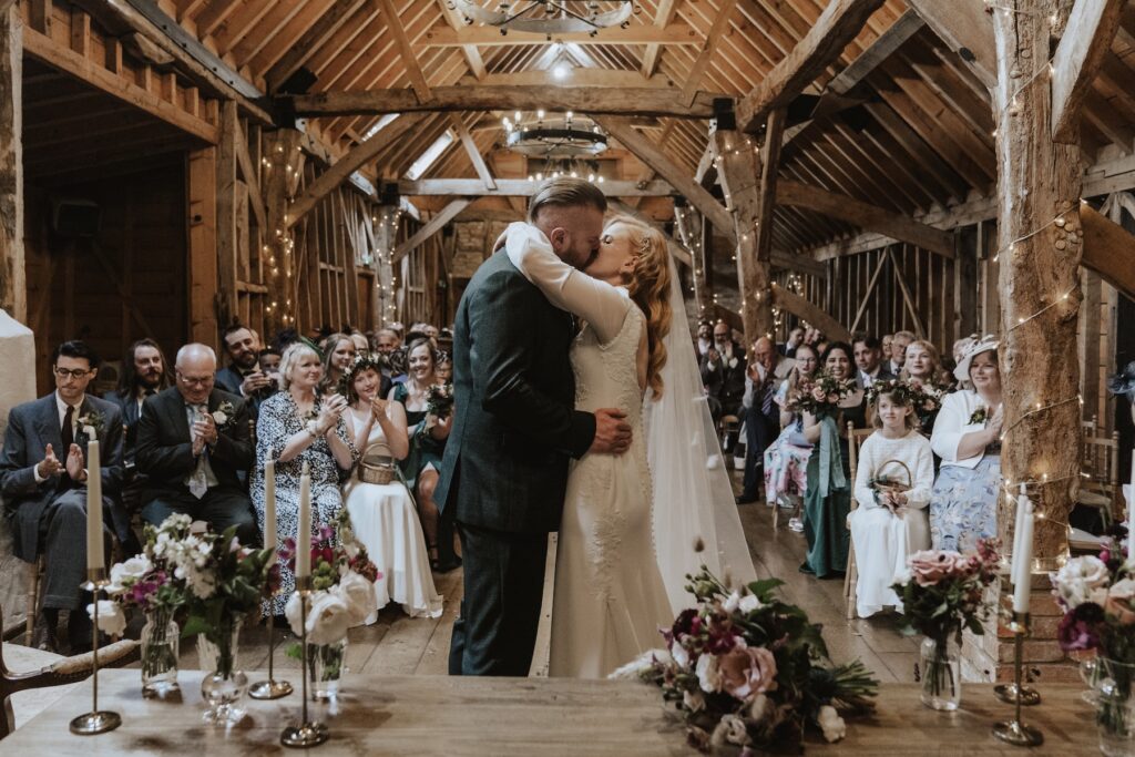 The first kiss during the ceremony at Bassmead Manor Barns in Cambridgeshire