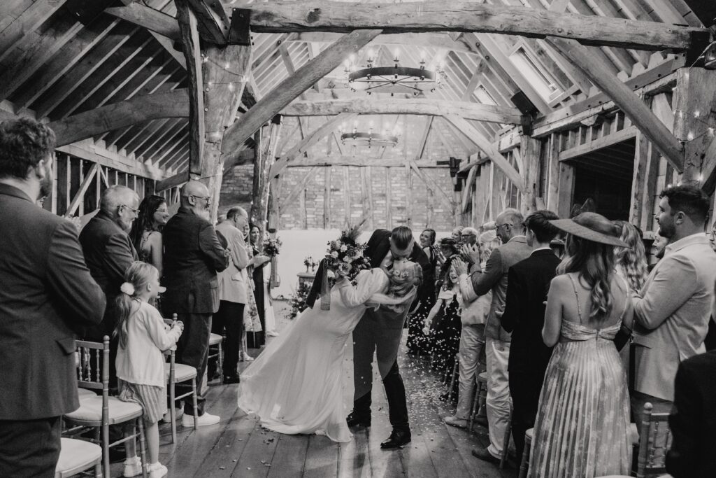 A couple walking down the aisle after their wedding at Bassmead Manor Barns in Cambridgeshire