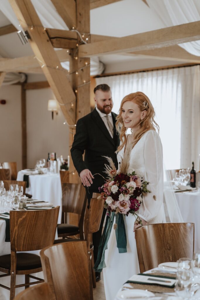 Candid moments of the couple looking at their wedding breakfast room decorated at Bassmead Manor Barns