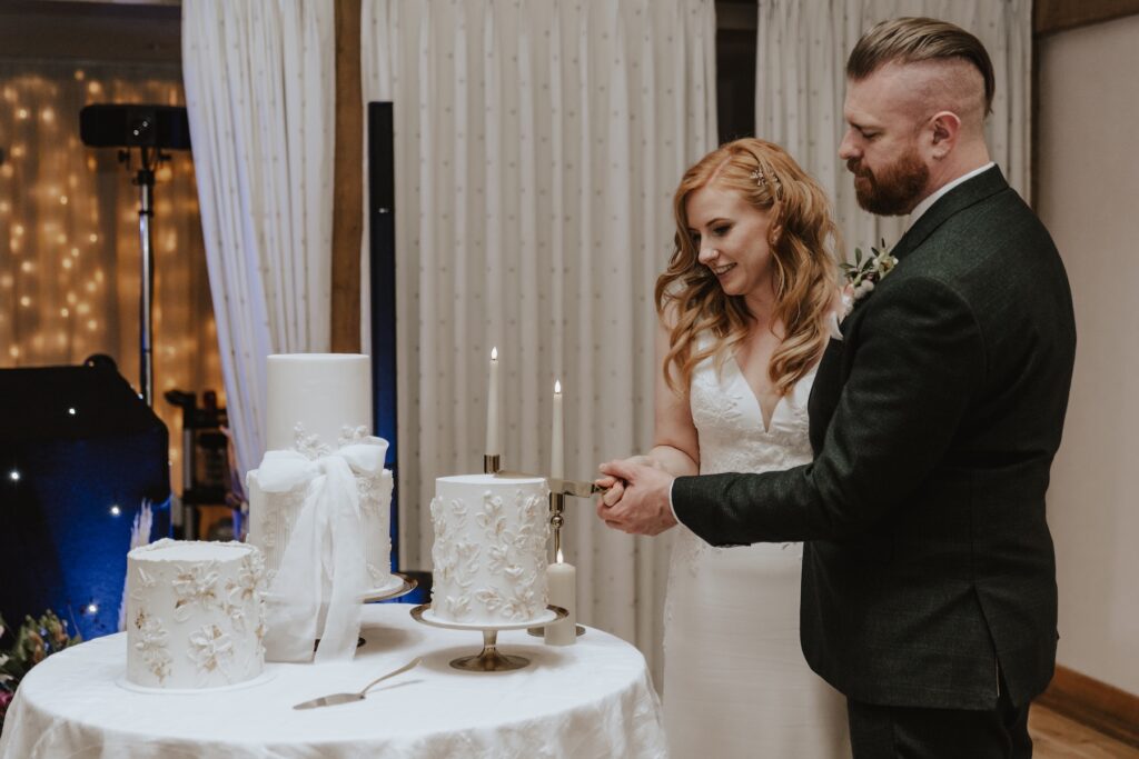 The couple cutting their cake at Bassmead Manor Barns in Cambridgeshire