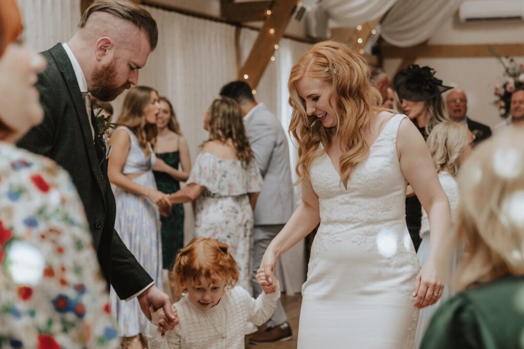 The bride and groom dancing with their daughter at Bassmead Manor Barns in Cambridgeshire