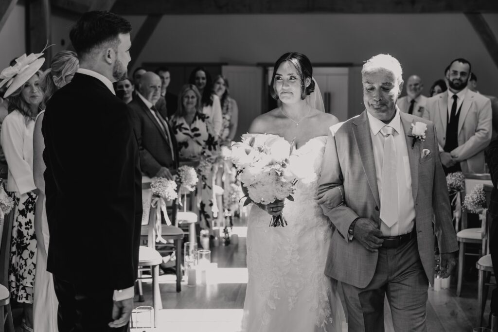 The bride walking down the aisle with her father at Easton Grange in Suffolk