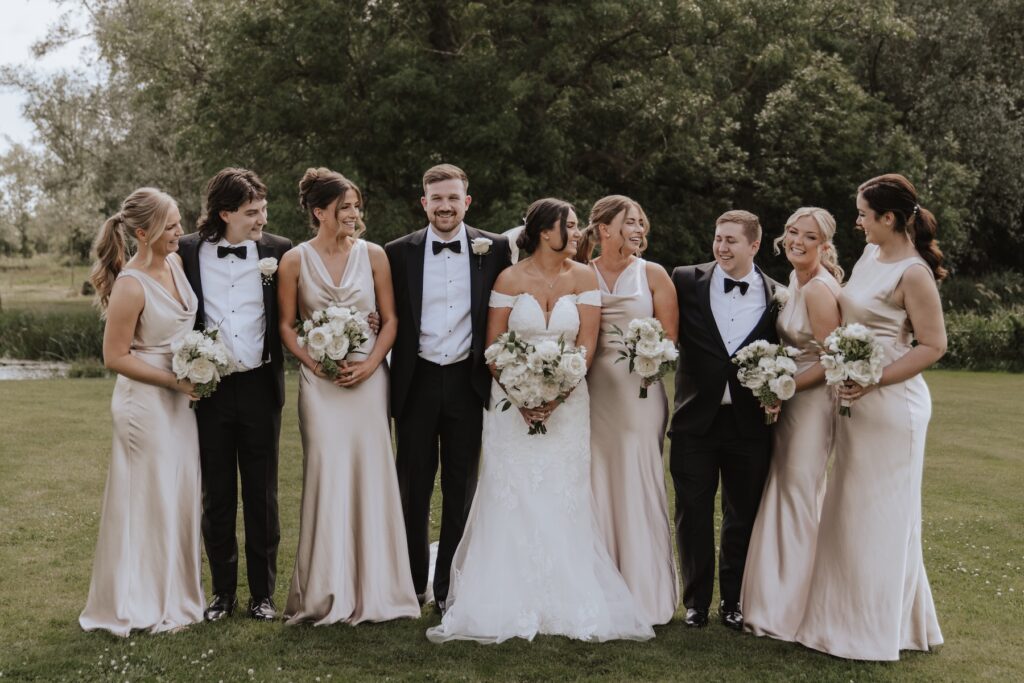The bride and groom with their wedding party having fun photos at Easton Grange in Suffolk