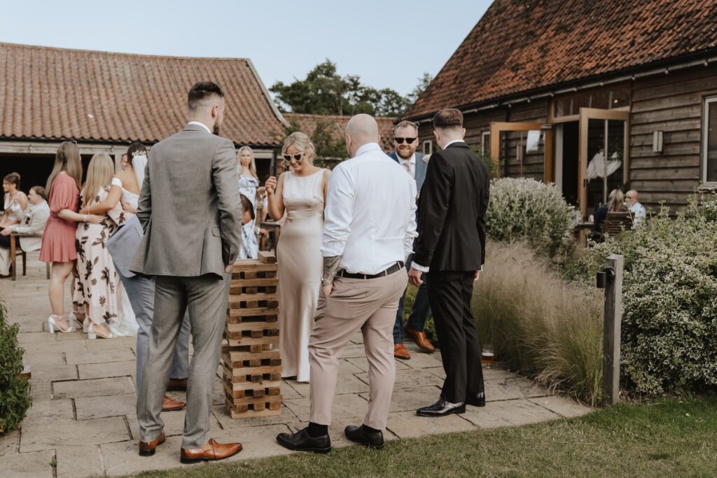 Candid captures of guests playing Giant Jenga in the evening at a wedding at Easton Grange in Suffolk