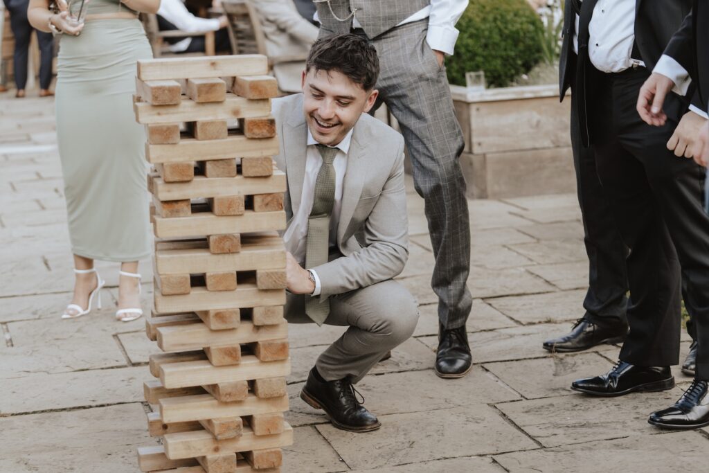 Candid photos of guests as they play giant Jenga in the evening reception of a wedding at Easton Grange in Suffolk
