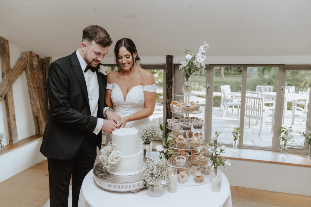A couple cutting their cake on their wedding evening in Suffolk at Easton Grange
