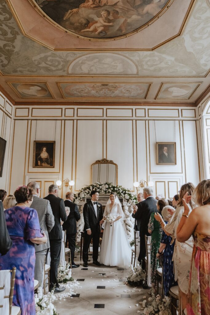 The bride and groom leaving the ceremony at Gosfield Hall in Essex