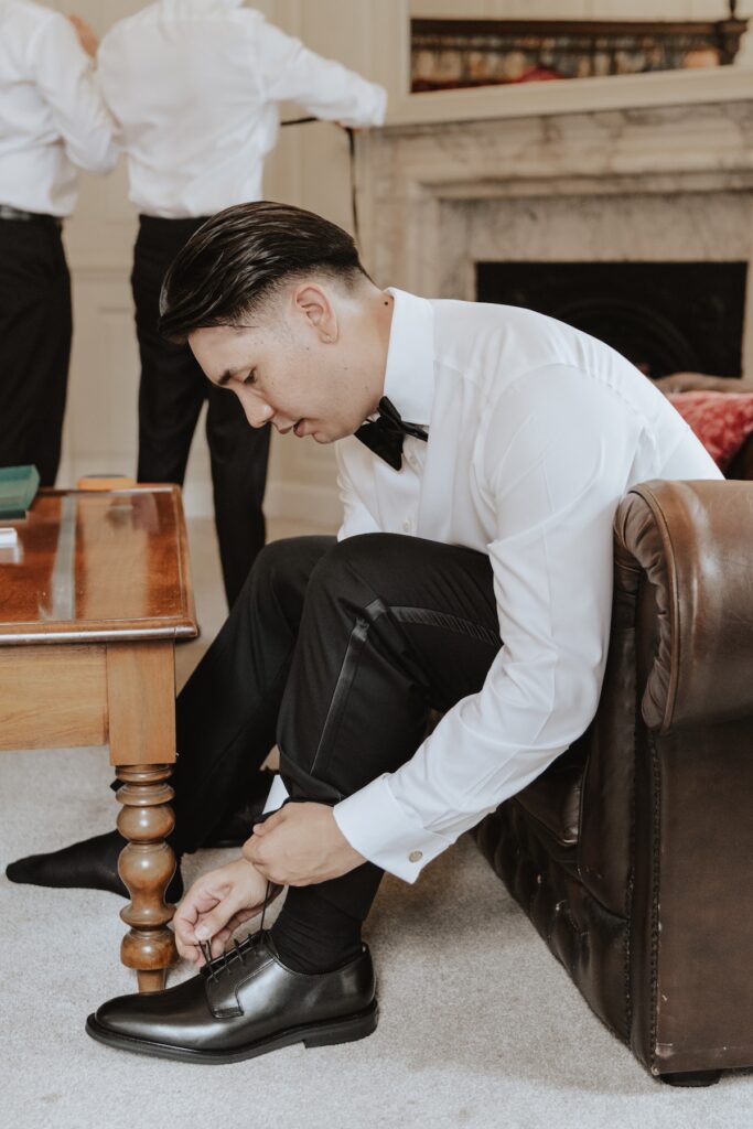 The groom putting his shoes on whilst getting ready at Gosfield Hall