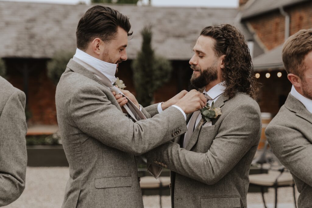 Groom adjusting tie in the on-site room at Copdock Hall before ceremony