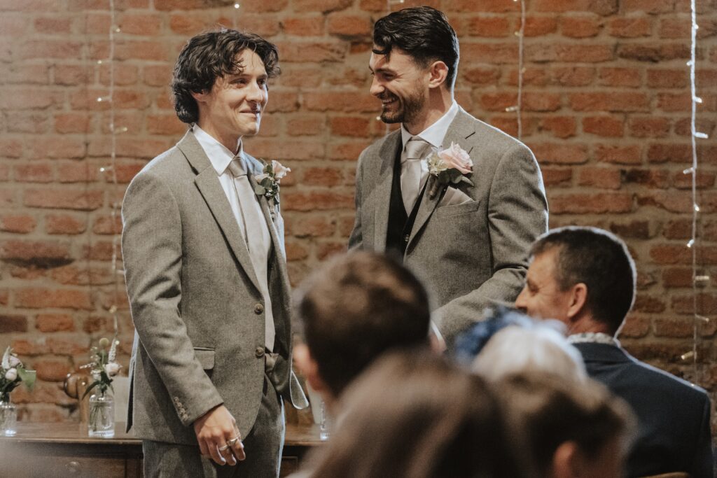 Groom smiling as bride walks towards him during Copdock Hall ceremony