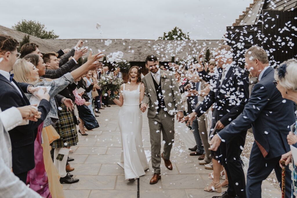 Bride and groom covered in floating paper confetti outside Copdock Hall