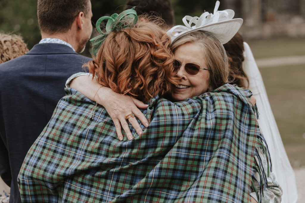 Relaxed outdoor drinks reception with guests laughing in Copdock Hall courtyard.