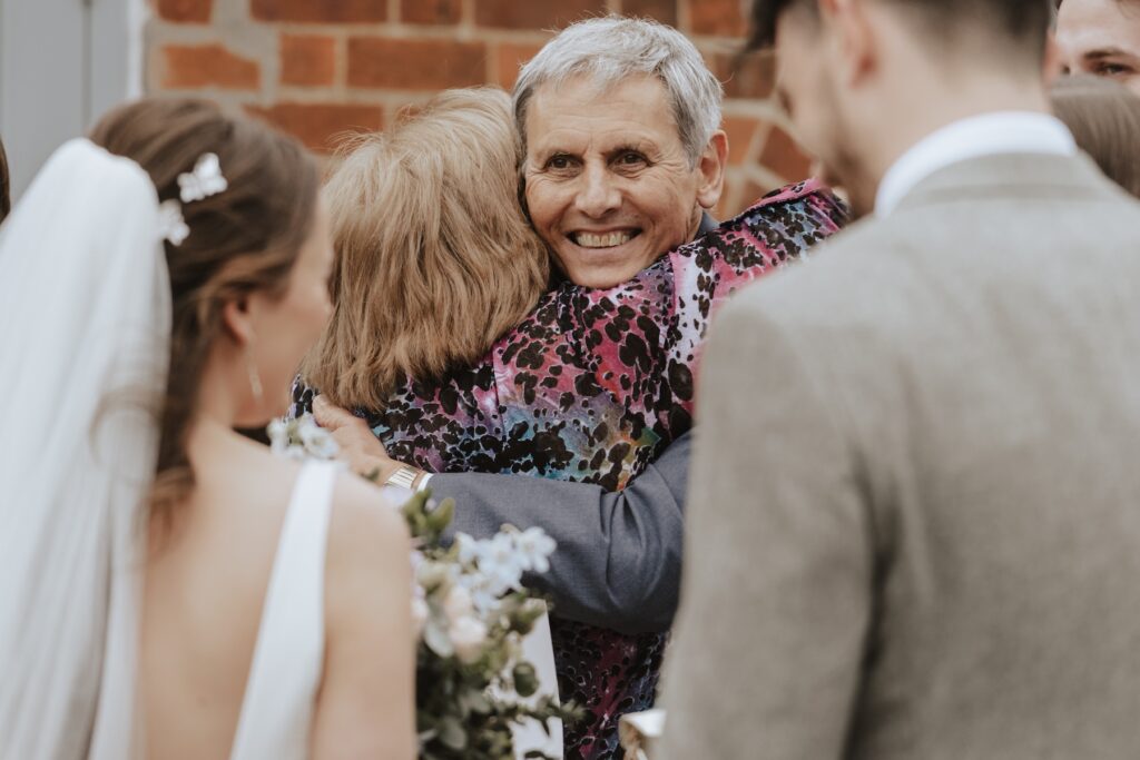 Hugging guests during drinks reception at Copdock Hall wedding in Suffolk