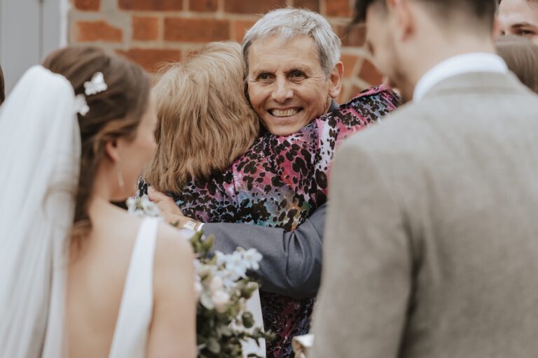 Hugging guests during drinks reception at Copdock Hall wedding in Suffolk