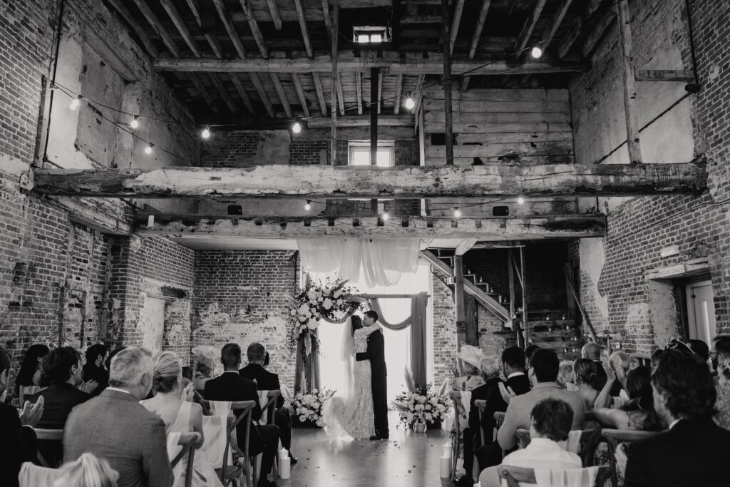 Rustic barn ceremony space with draping and floral details in Norfolk