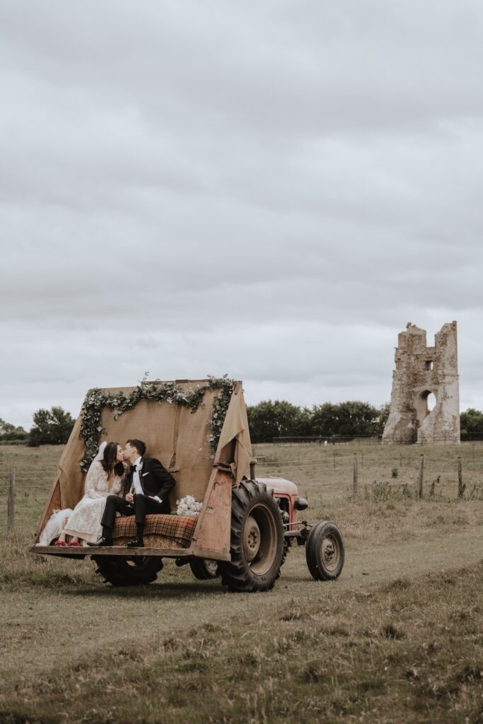 Wedding party enjoying tractor ride across fields at Godwick Hall