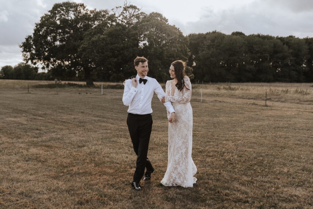 Couple walking in golden hour light outside Godwick Hall wedding venue