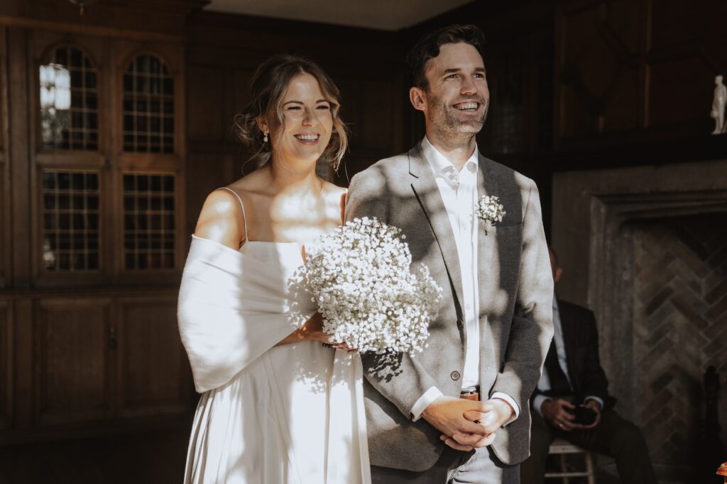 Couple exchanging rings in front of elegant bookcases during the morning ceremony