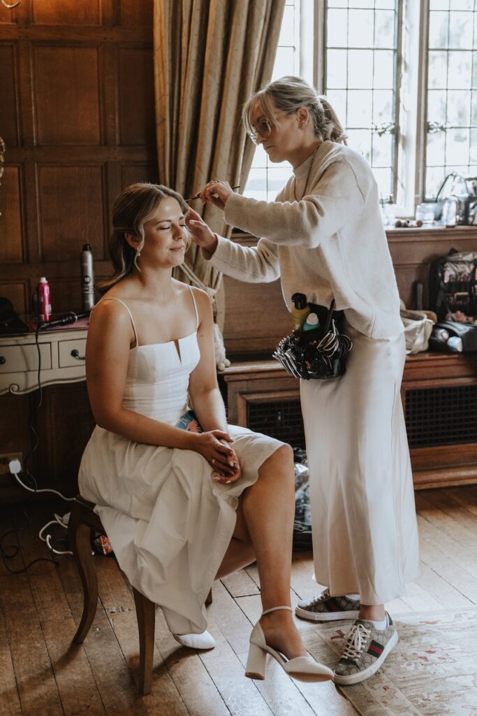 Bride having her makeup done in soft morning light at Hengrave Hall bridal suite